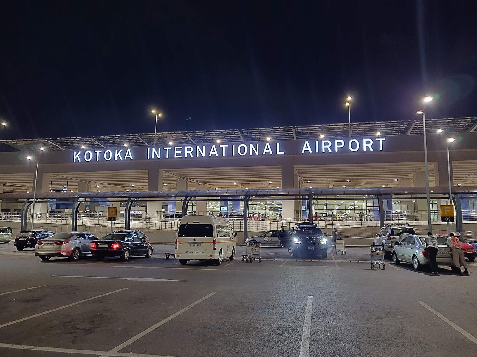 Front of Terminal 3 at Accra International Airport at night, with the sign showing its former name, Kotoka International Airport
